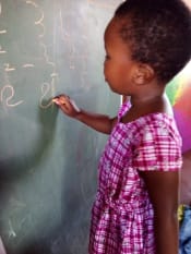 young girl writing on chalkboard