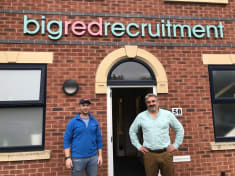 two men standing in front of a brick built office 